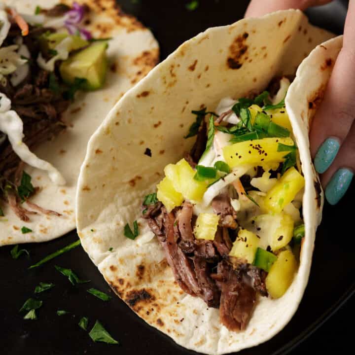 A taco made with beef carnitas with salsa on top.