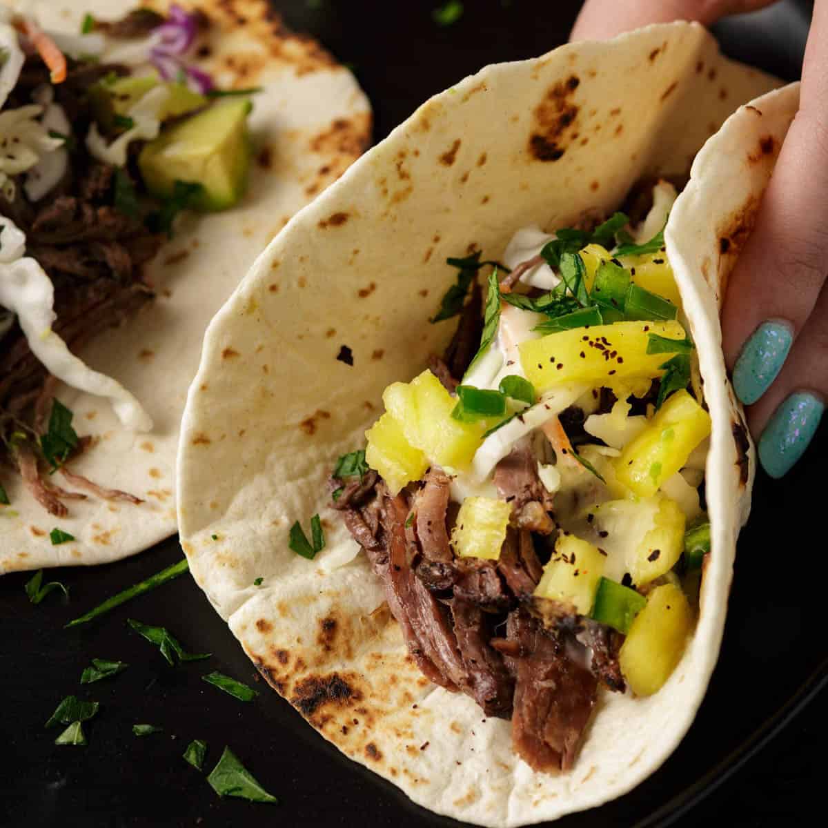 A taco made with beef carnitas with salsa on top.