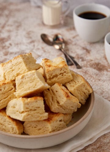 Square biscuits in a bowl with coffee cups.