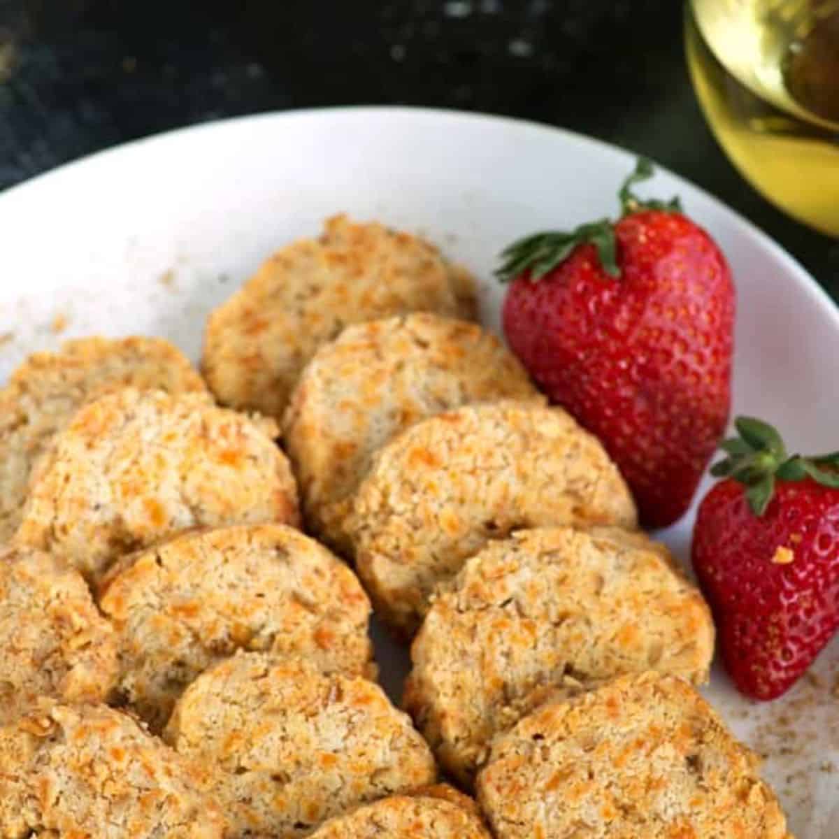 A platter of old bay cheese wafers with some strawberries.