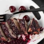 A platter of grilled pork tenderloin with cherry sauce.