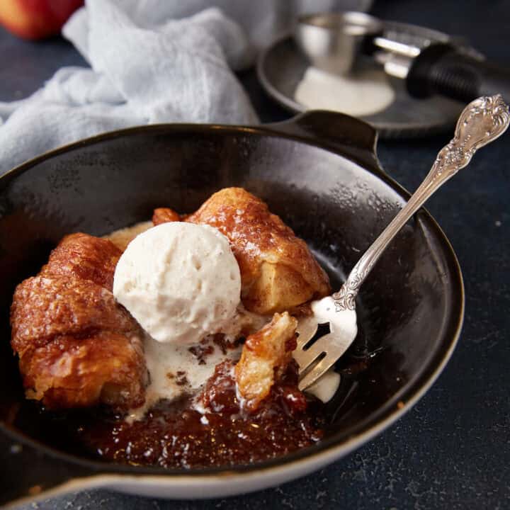 An apple dumpling with a scoop of ice cream and a fork.