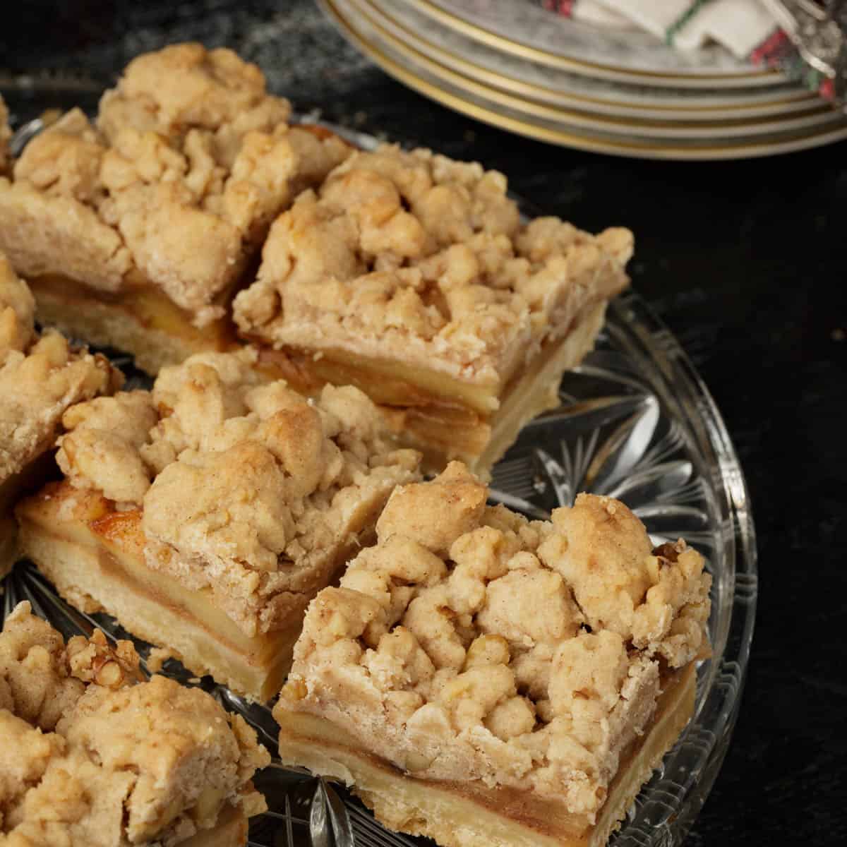 A clear glass platter filled with apple bars.
