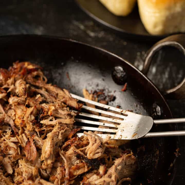 Carnitas being crisped in a skillet on the stove.