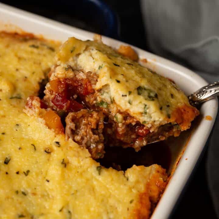 Grit topped chili casserole with a serving spoon.