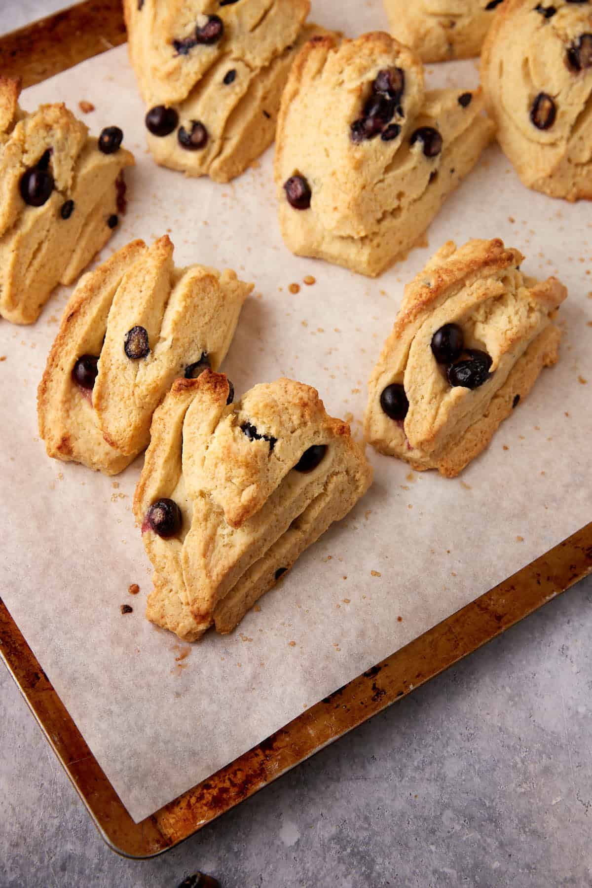Baked blueberry scones on a cookie sheet.