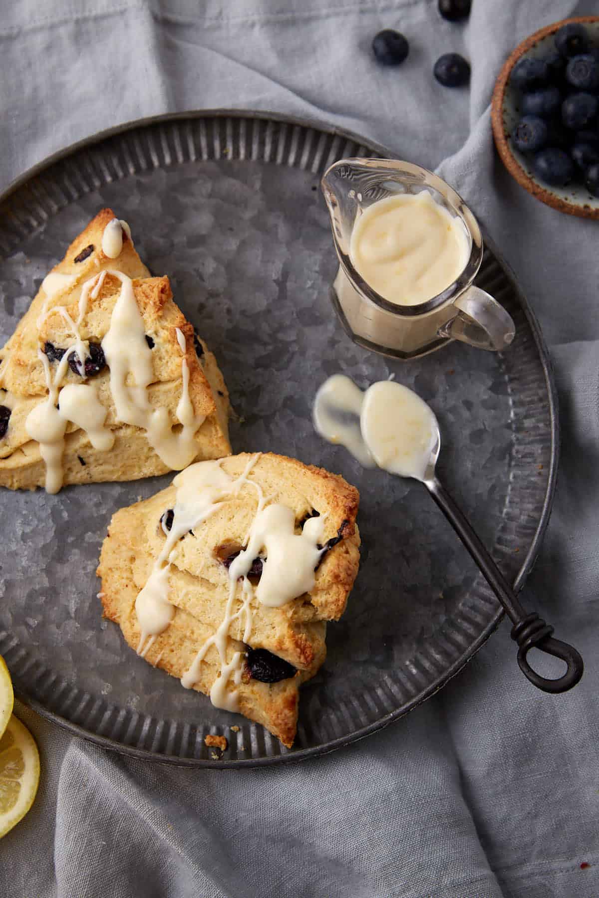 Two blueberry scones on a platter drizzled with a glaze. 