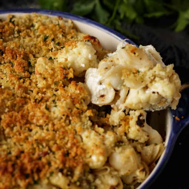 Cauliflower pasta being removed from a baking dish.