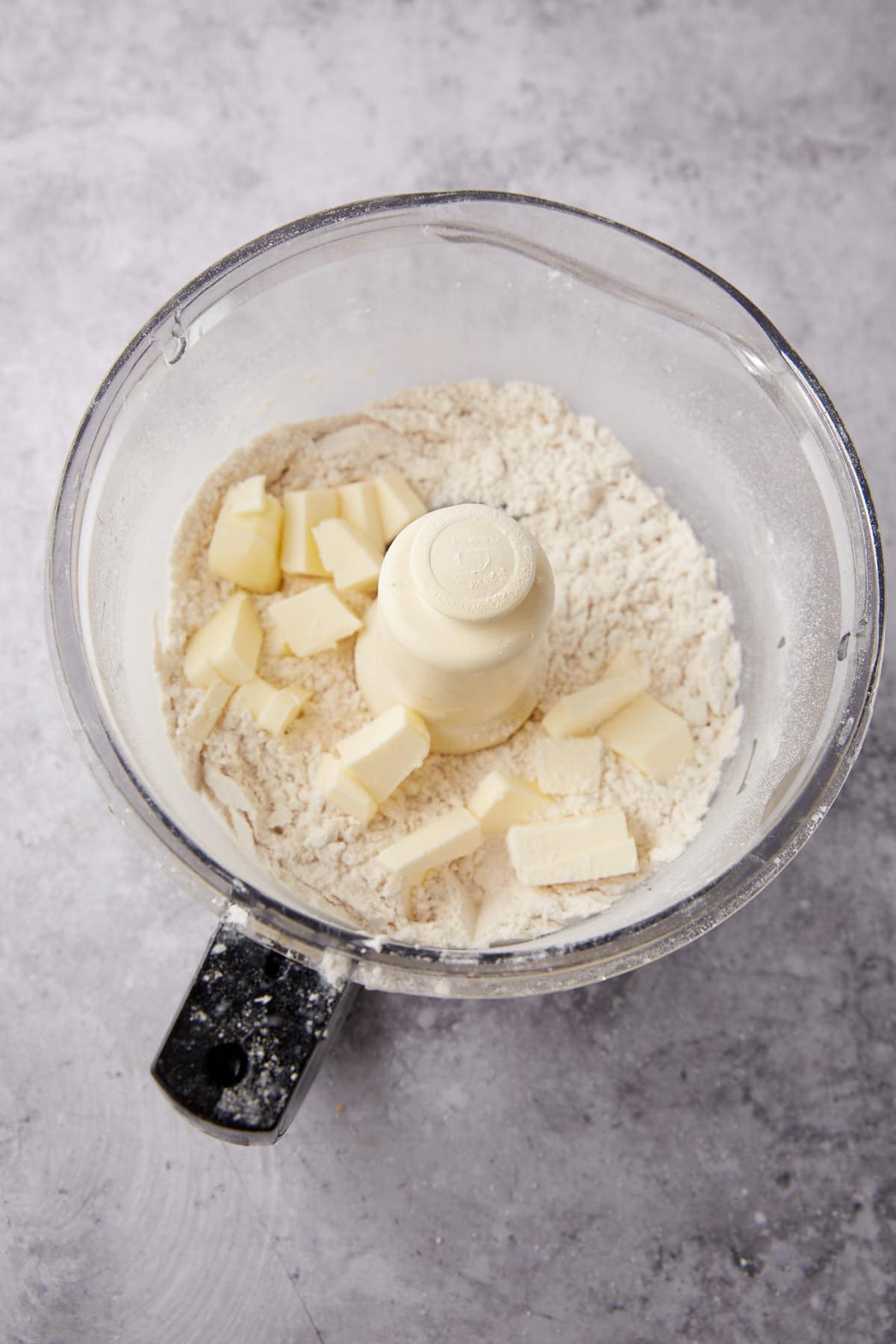 A food processor with chunks of butter in the flour mixture.