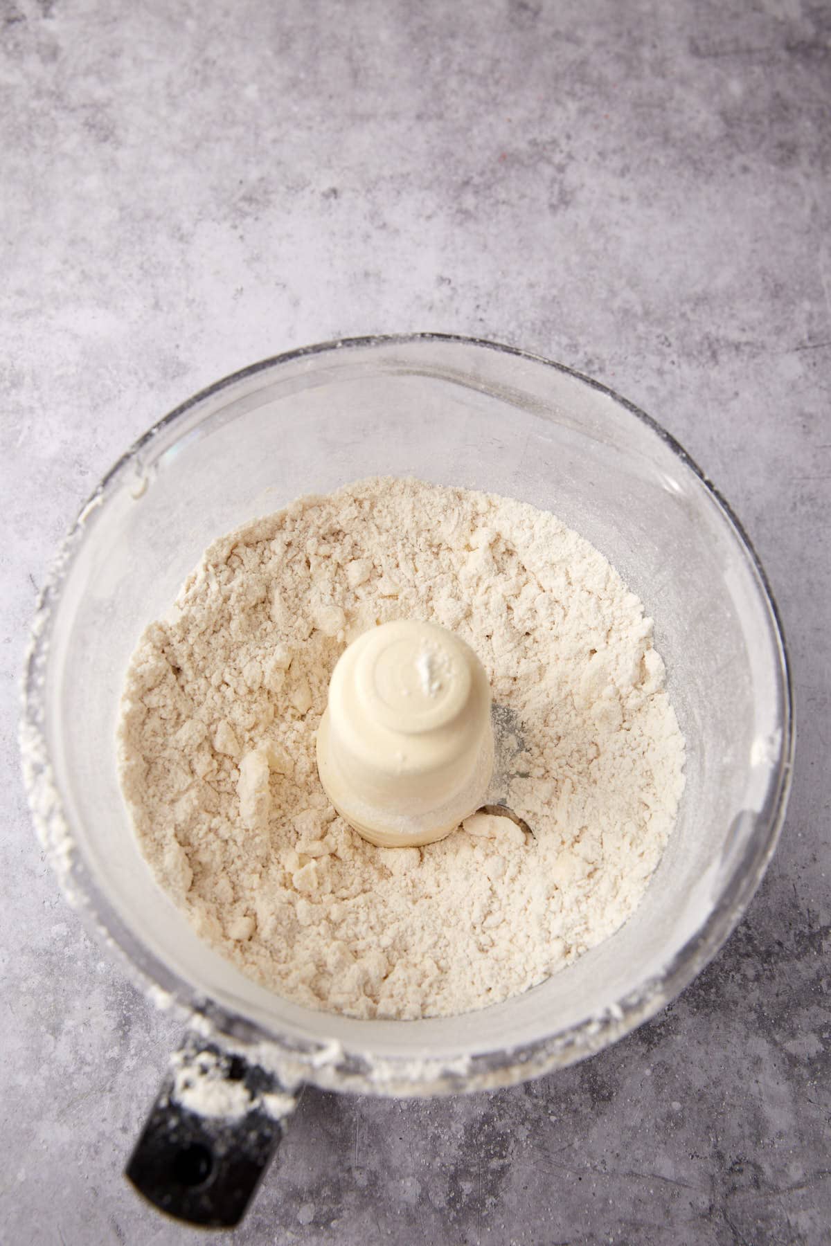 A food processor with butter incorporated into the flour mixture.
