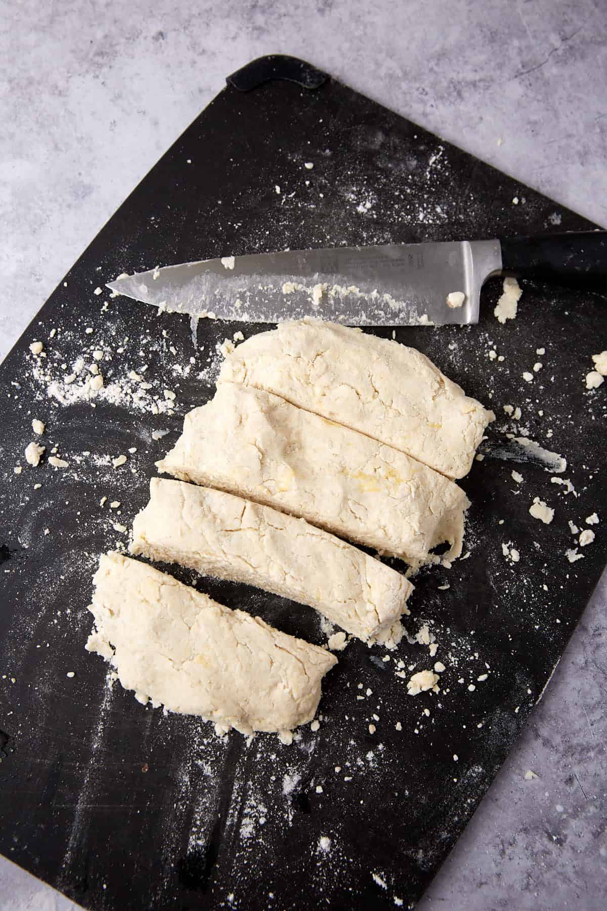 Biscuit dough cut into fourths on a cutting board.