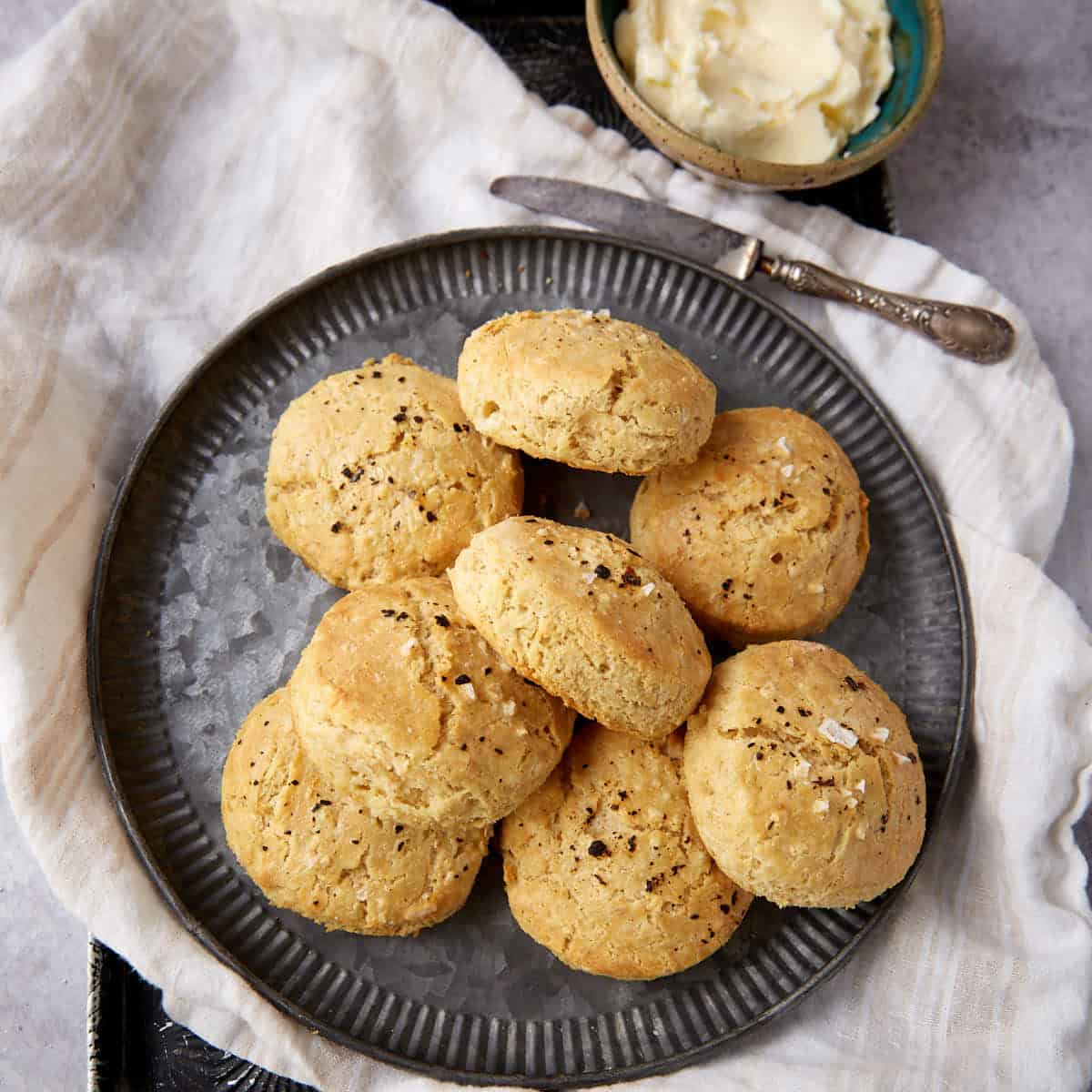 A platter of gluten-free biscuits next to a bowl of butter.