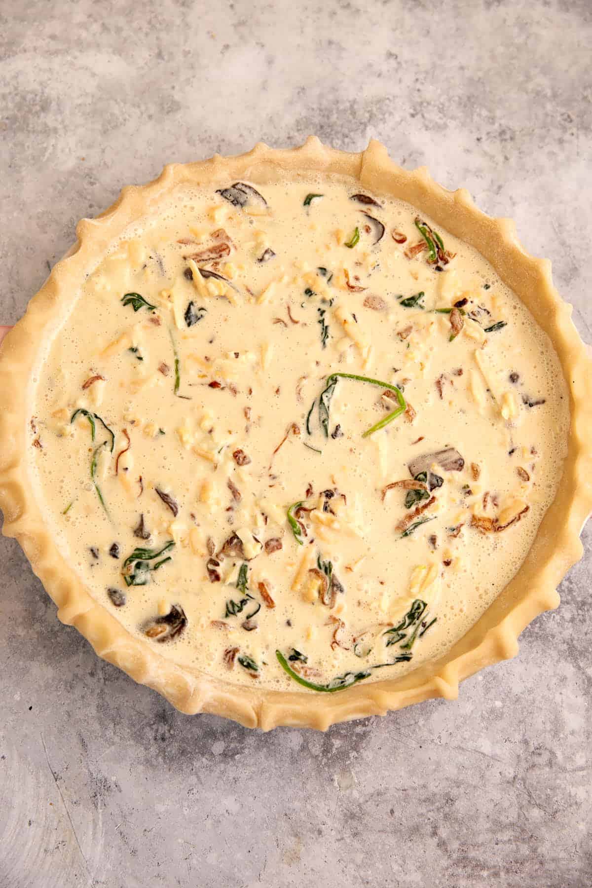 The quiche filling poured into a pie crust.