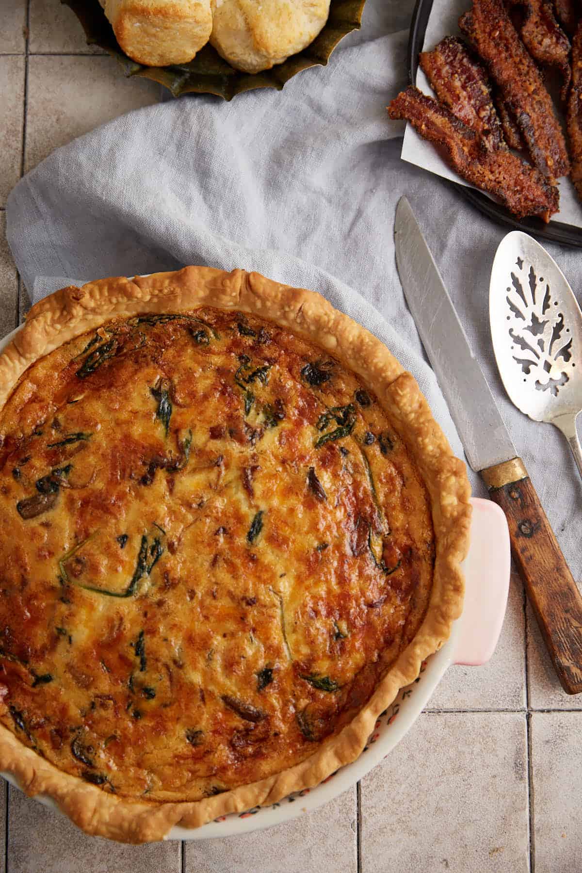 A baked spinach quiche next to a pie server.