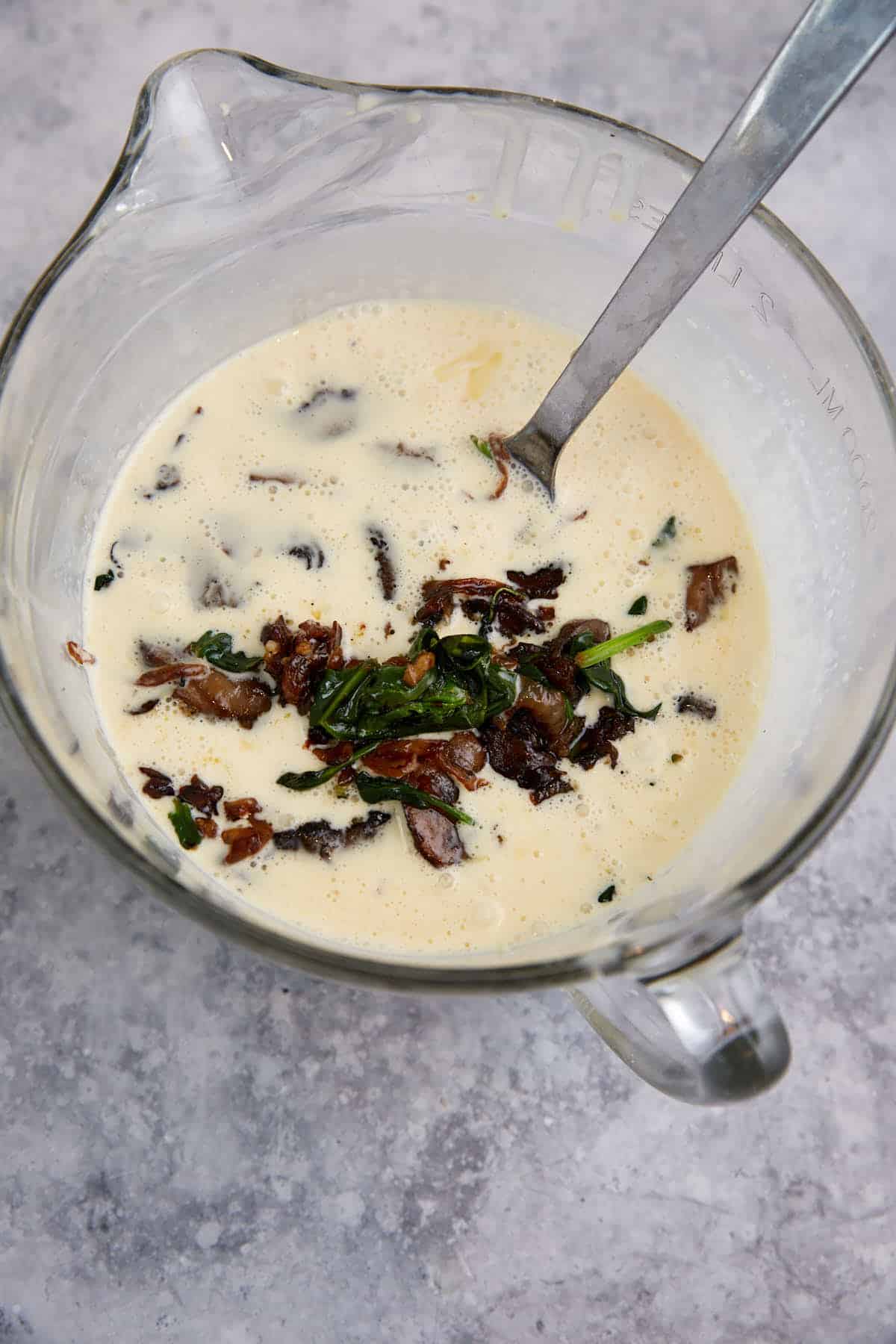 Veggies added to the egg mixture in a measuring bowl.