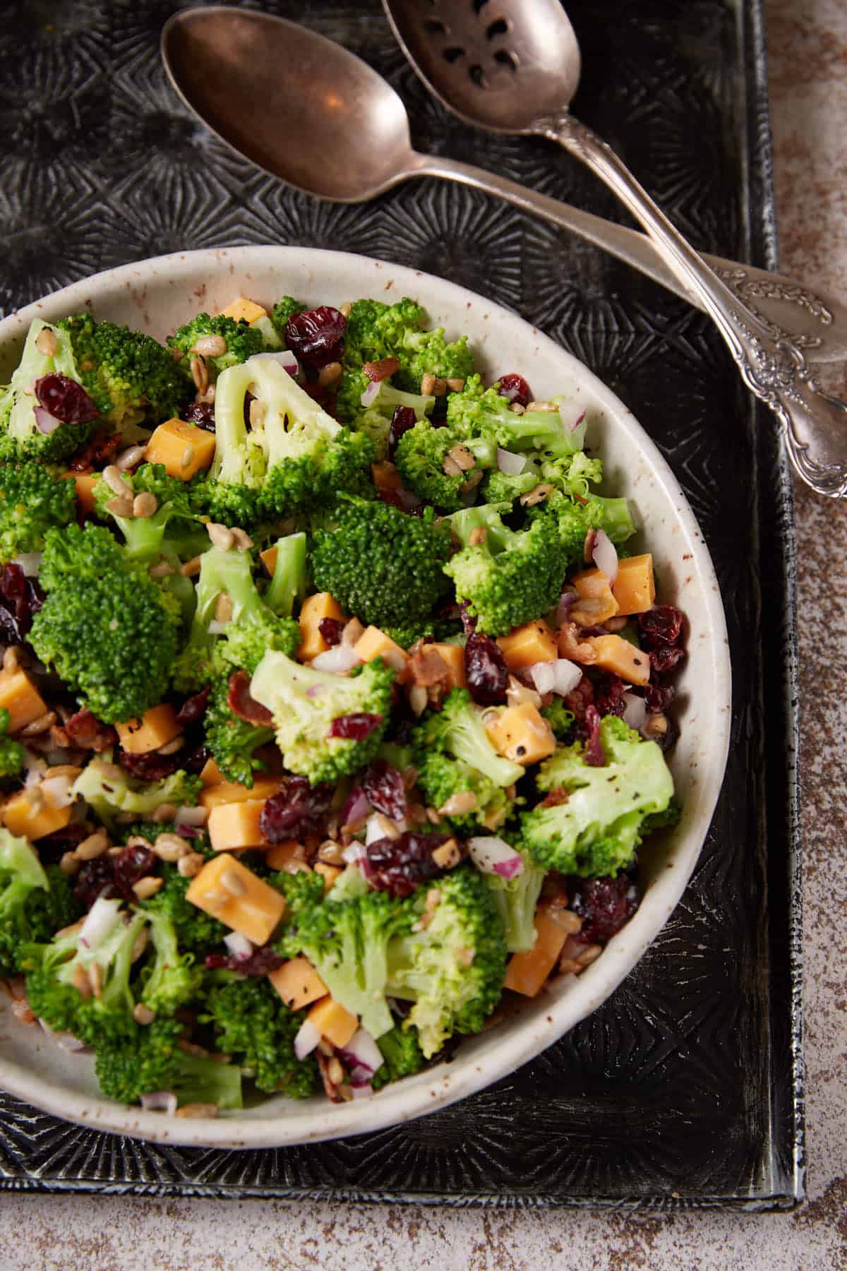 A bowl of broccoli salad on a serving tray.