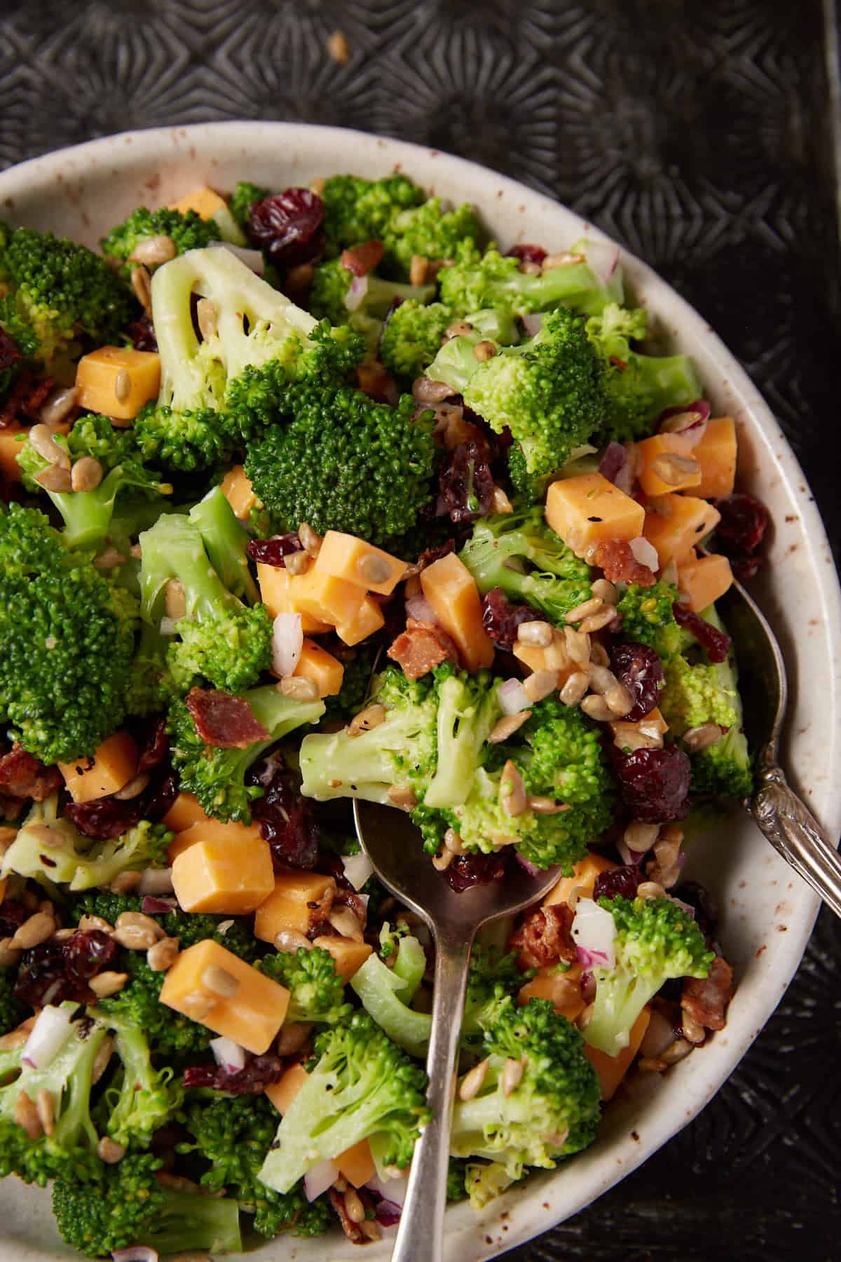 A bowl of broccoli salad with a serving spoon.