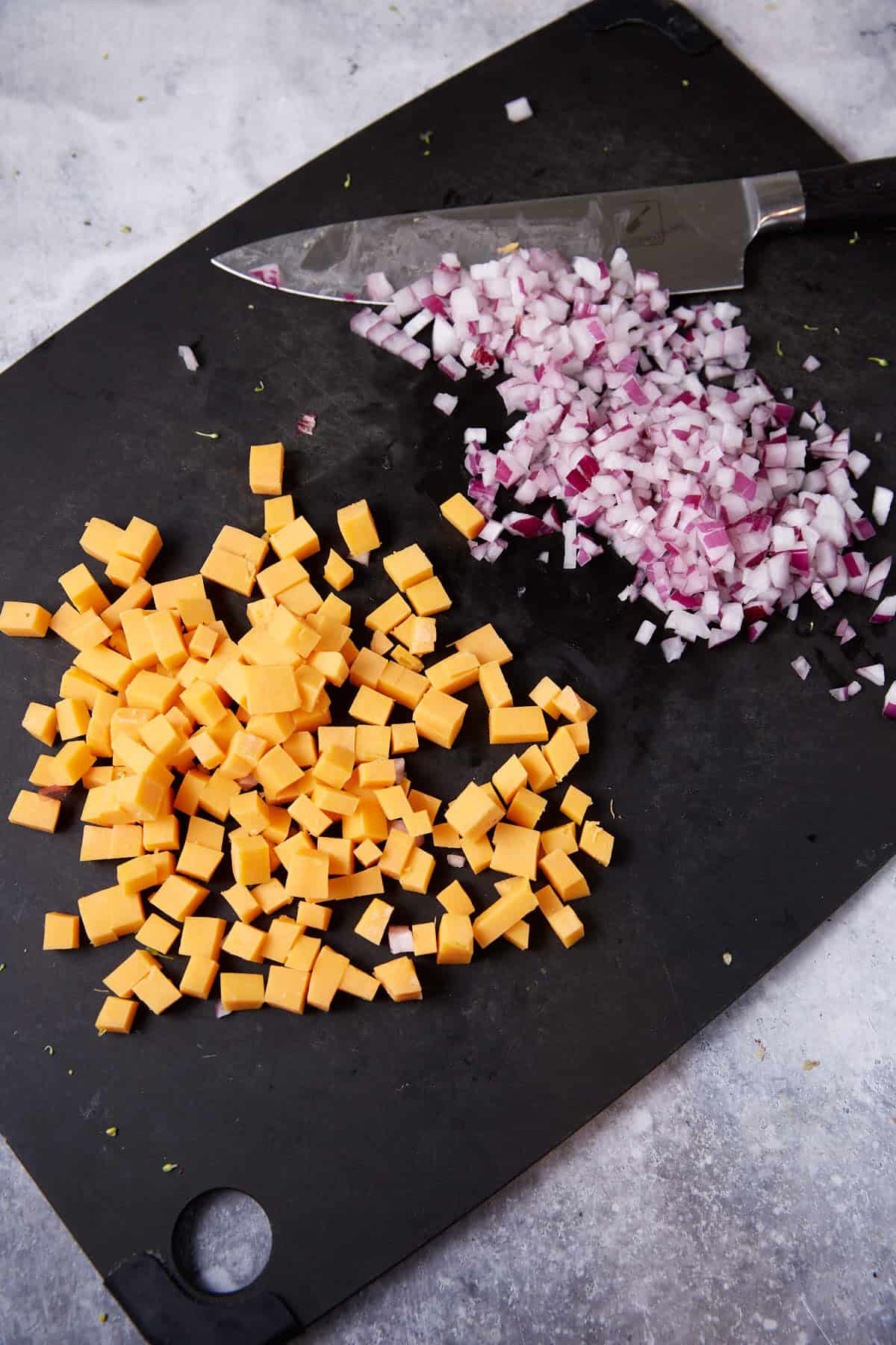 Chopped cheese and onions on a cutting board.