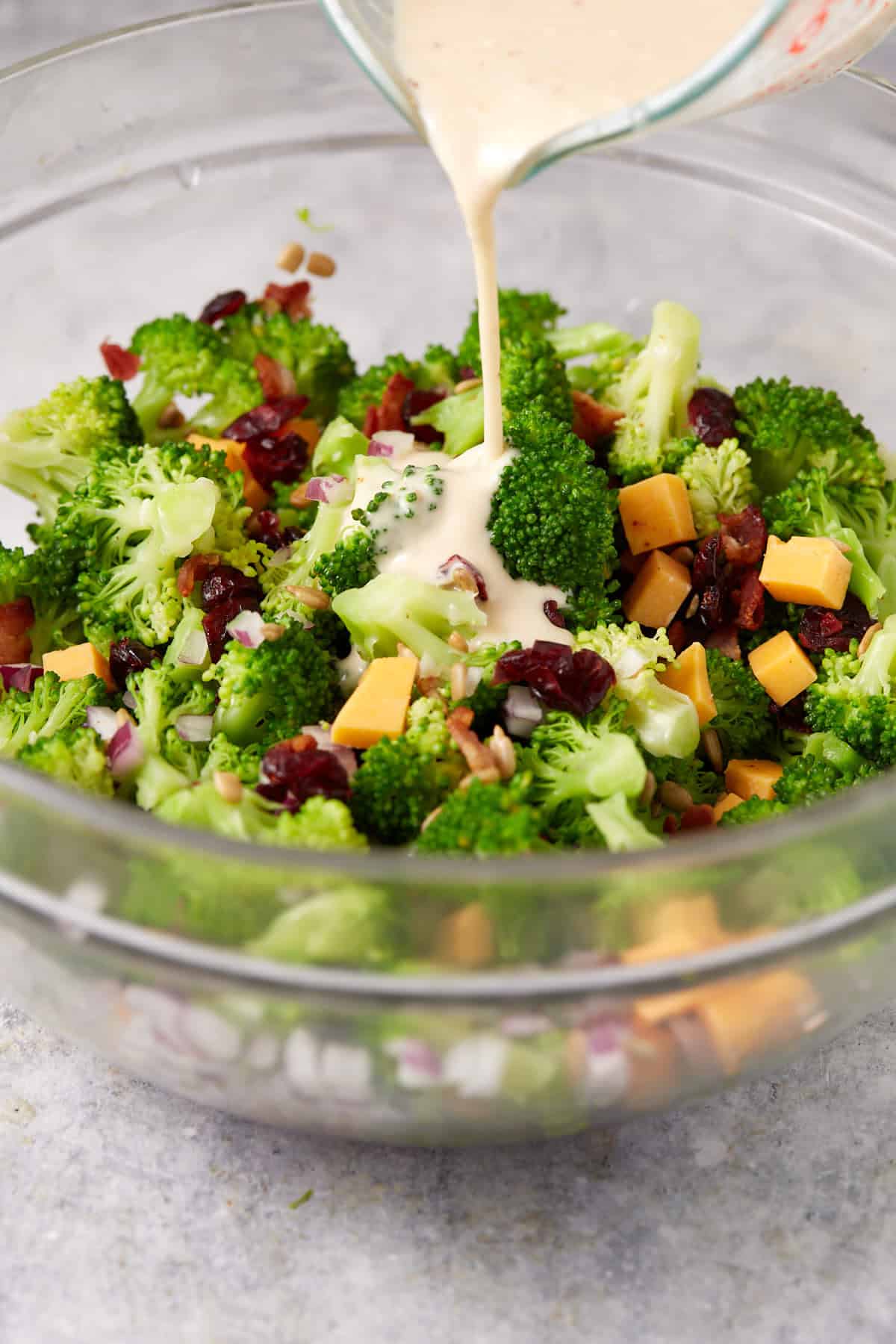 Dressing being poured over a broccoli cranberry salald.