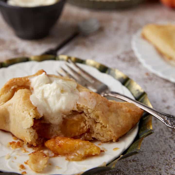 A glazed peach dumpling on a plate with a fork.