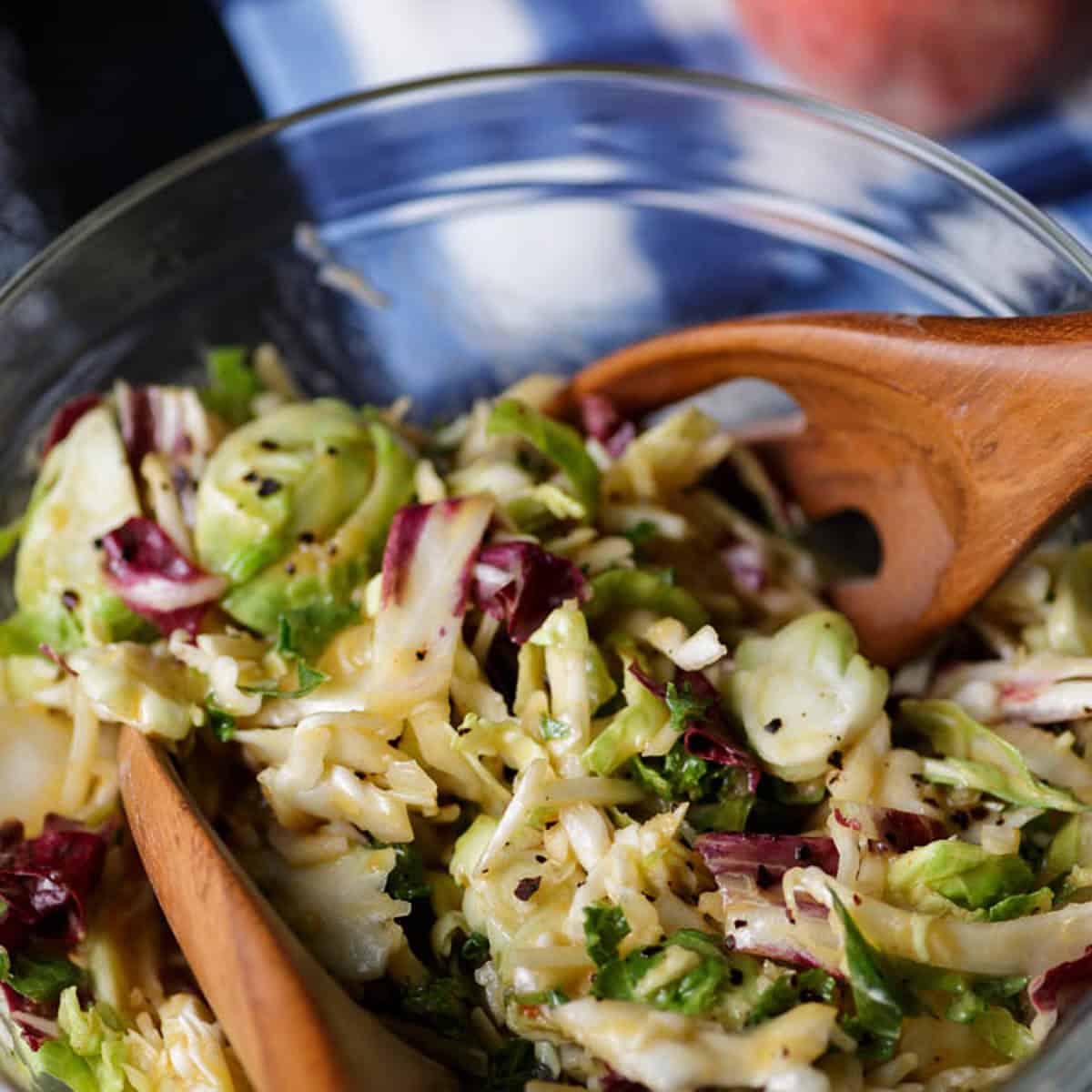 A bowl of peach coleslaw without mayo in a bowl with wooden spoons.
