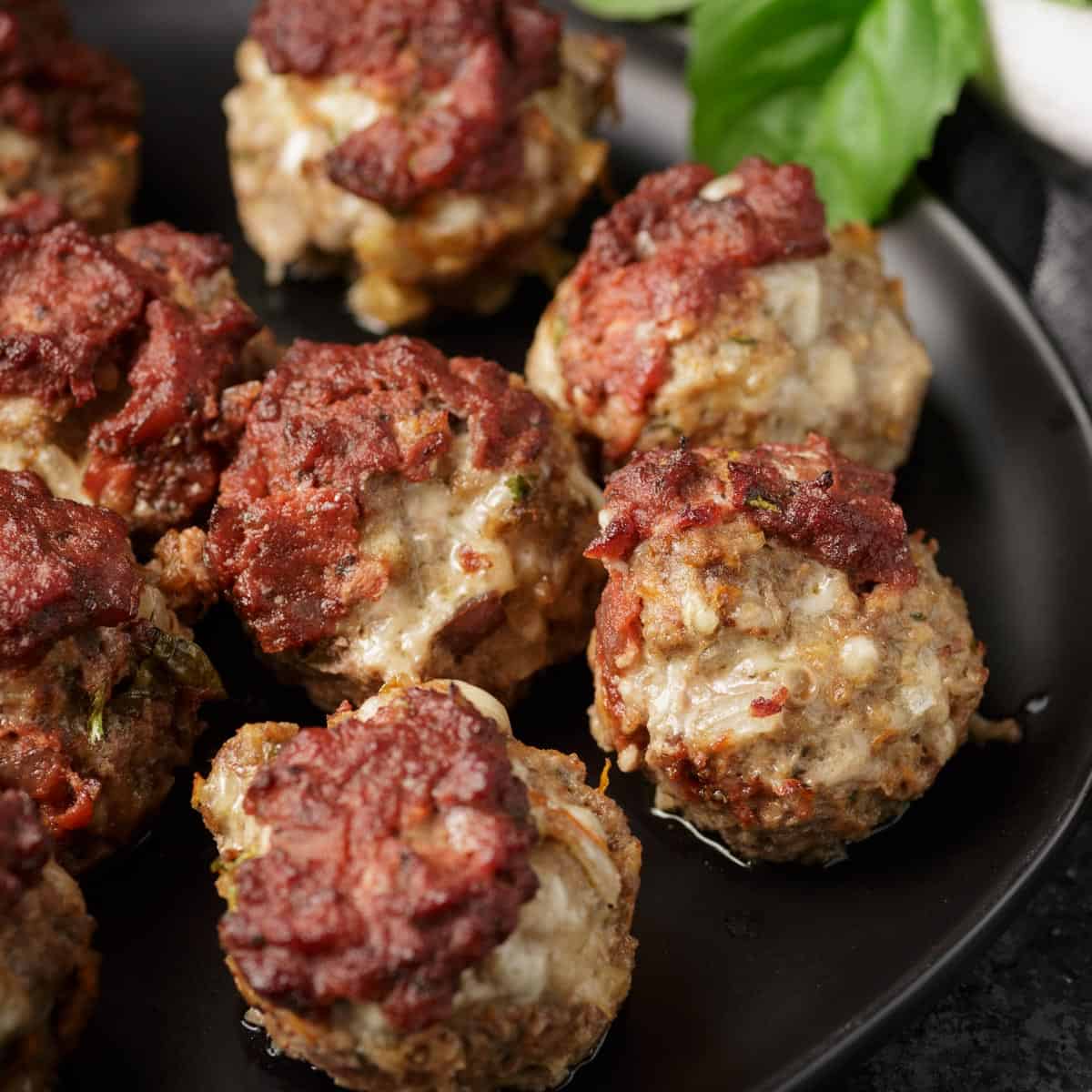 Meatloaf muffins topped with marinara sauce on a platter.