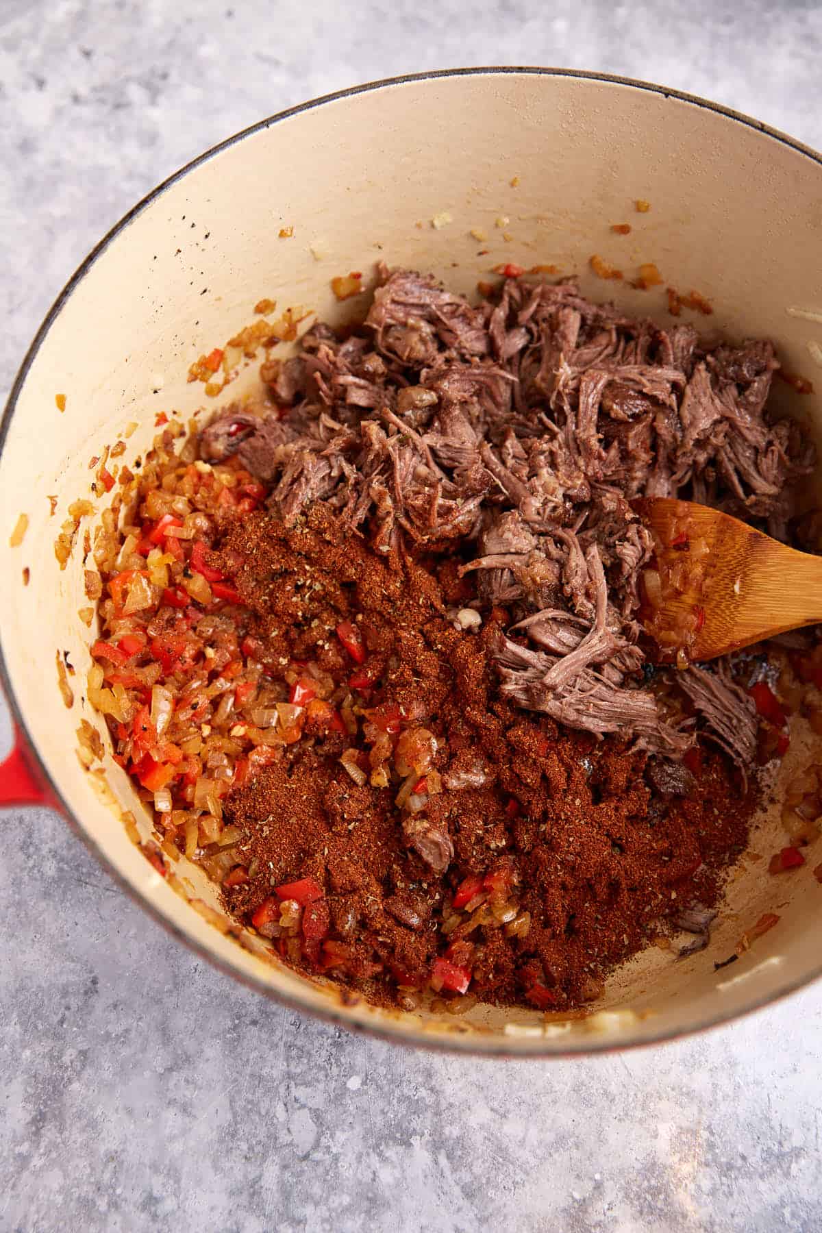 Shredded beef added to a Dutch oven.