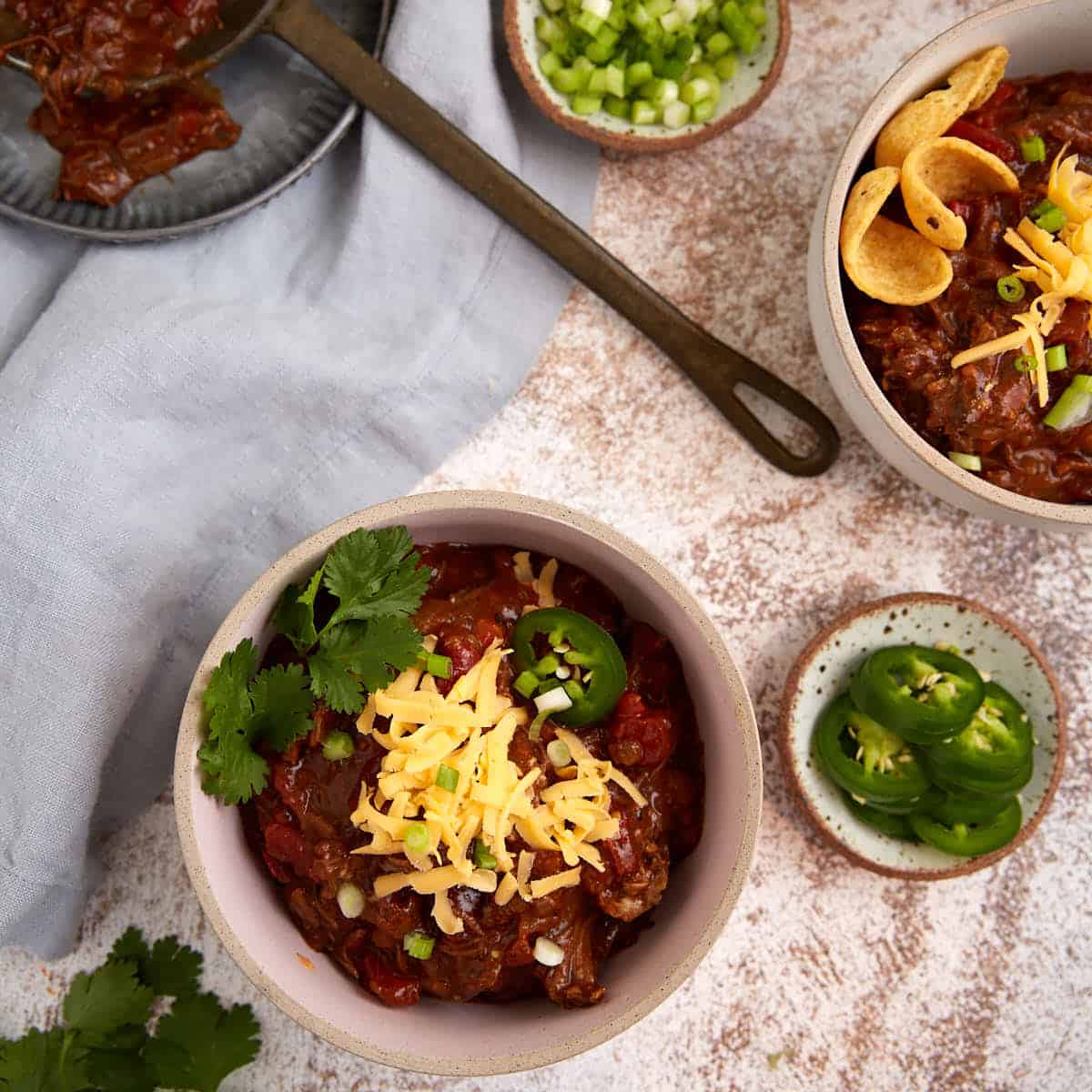 Bowls of short rib chili topped with cheese.