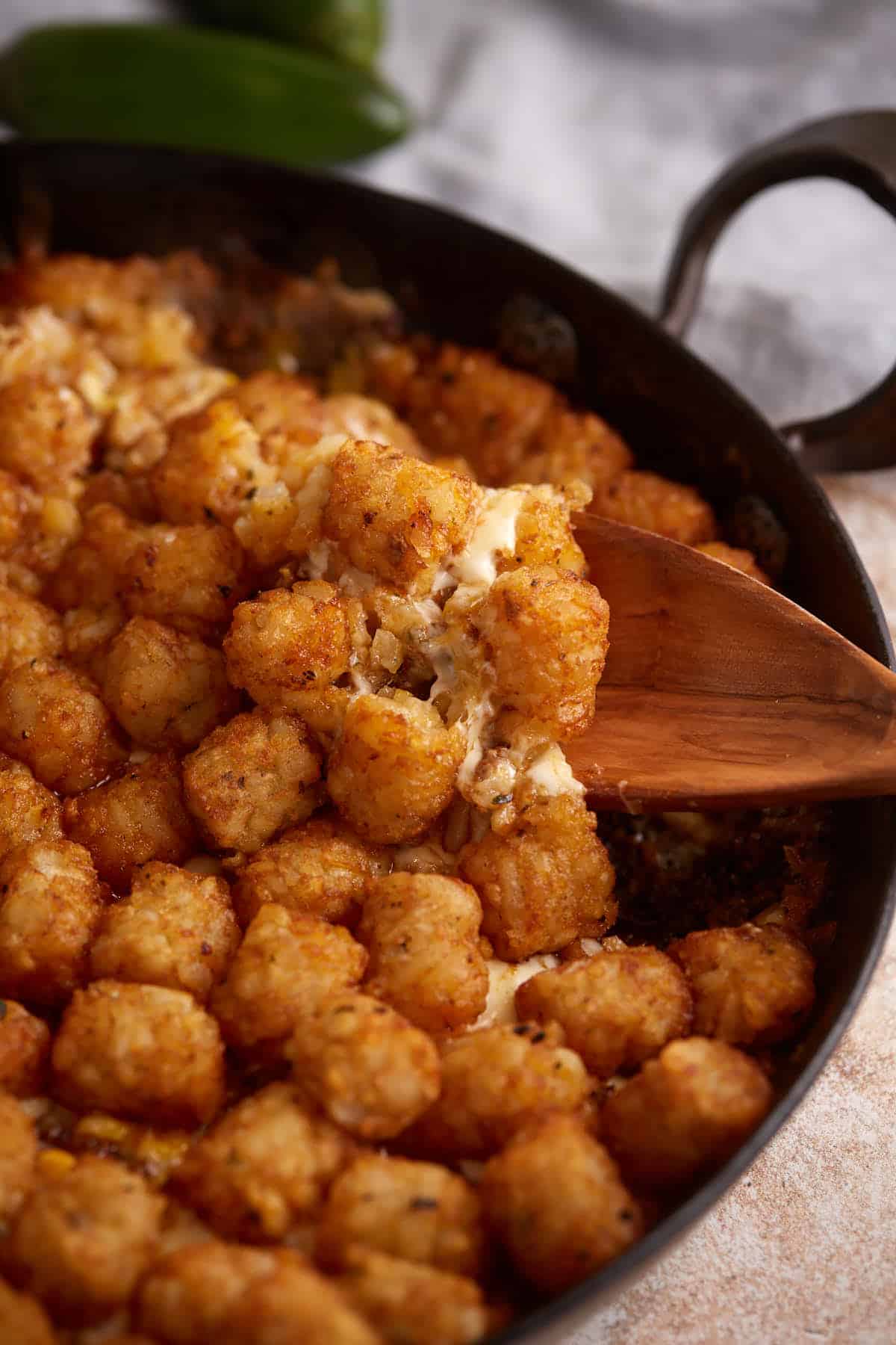 A spoon full of tater tot casserole with ground beef.