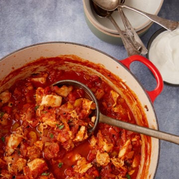A ladle scooping out chicken chili from a Dutch oven.