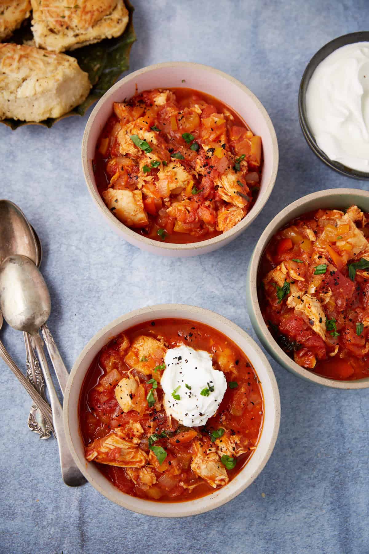 Bowls of chicken chili next to a bowl of scour cream.
