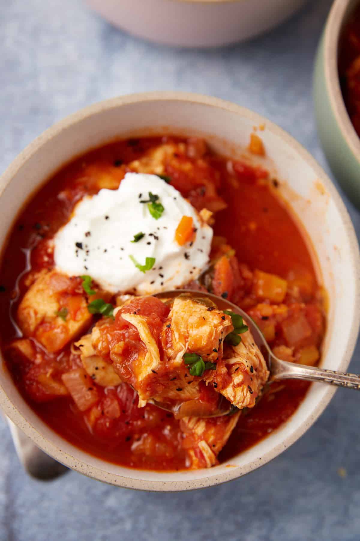 A bowl of chicken chili with sour cream on top.