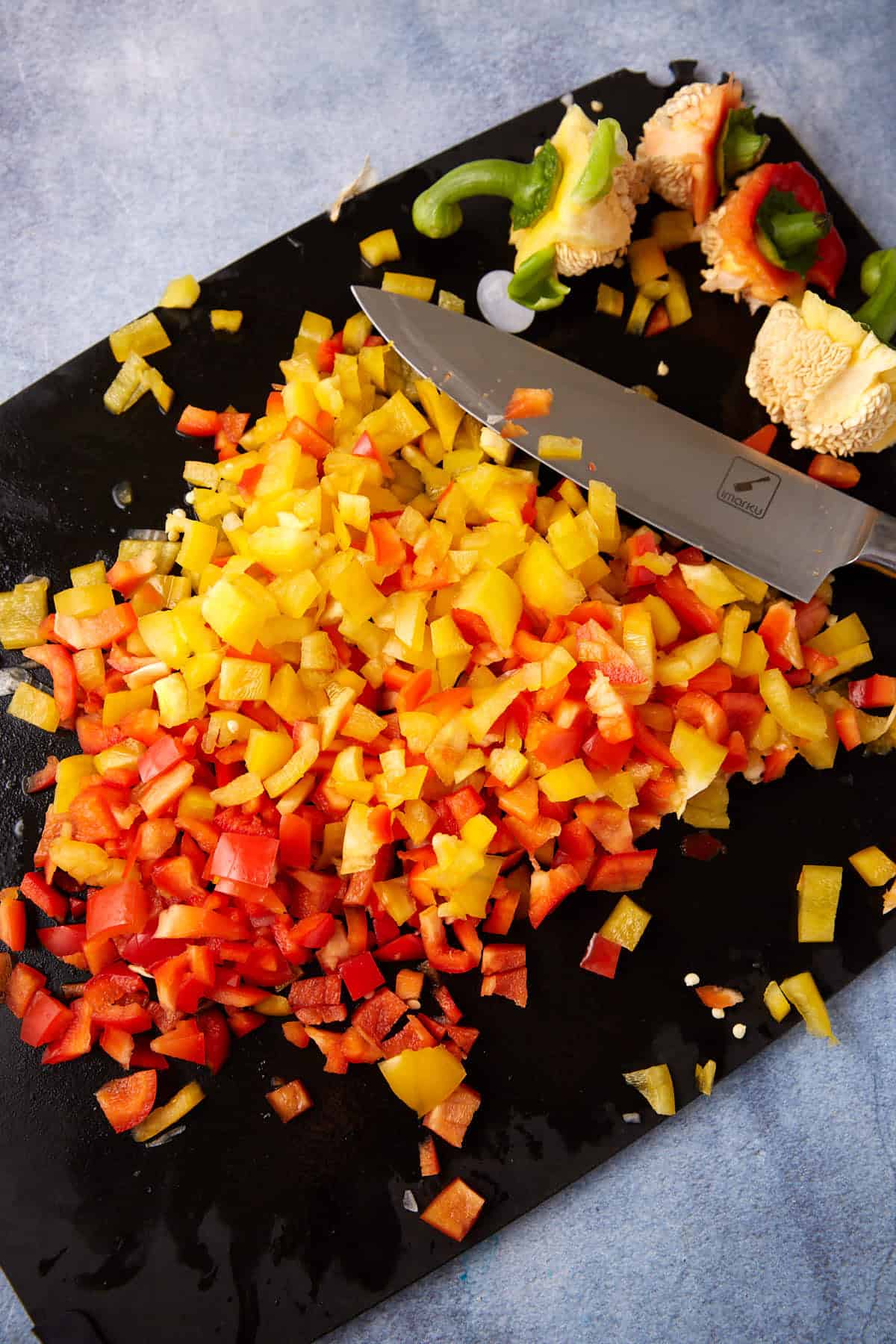 Red and yellow peppers chopped on a cutting board.
