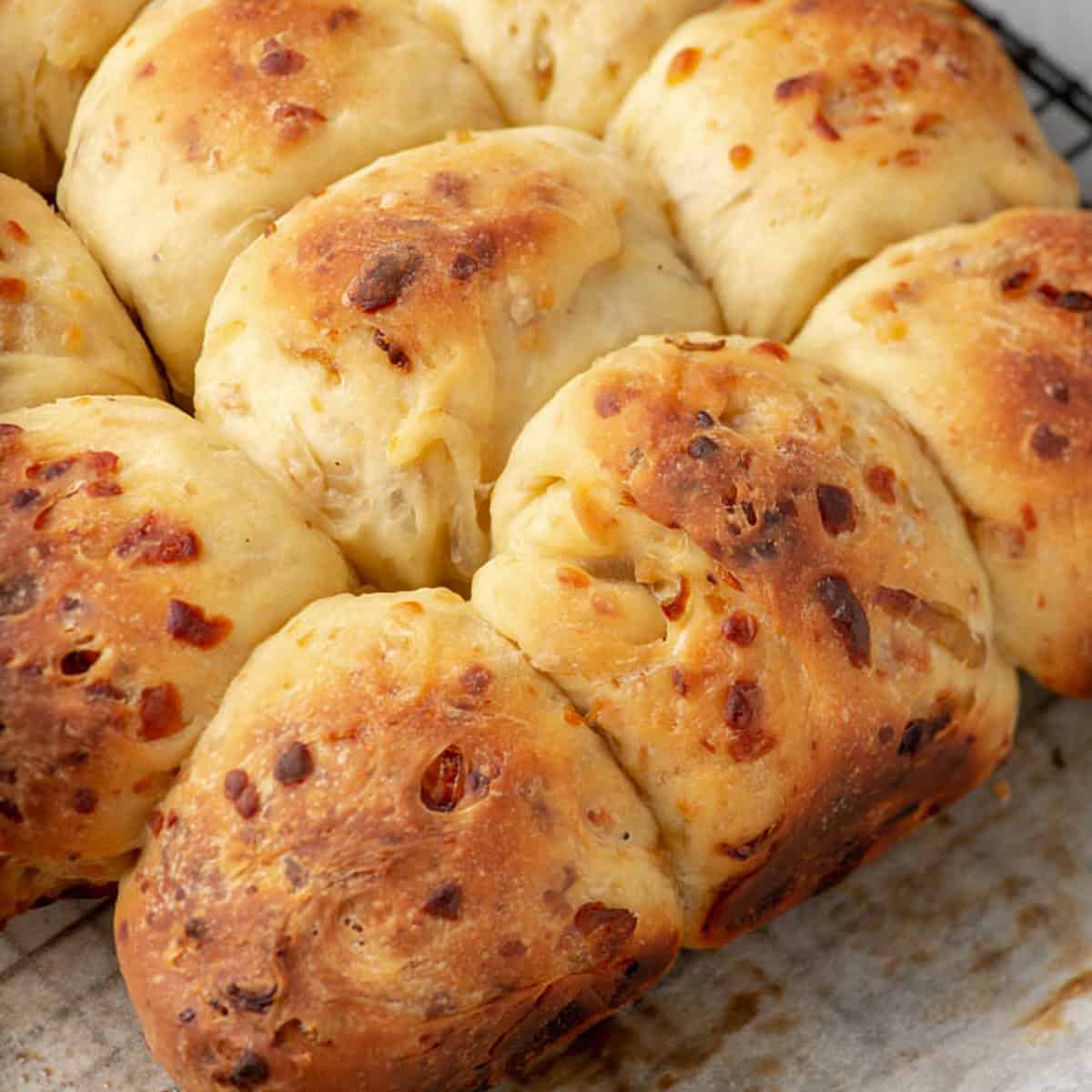 A batch of onion rolls on a wire rack.