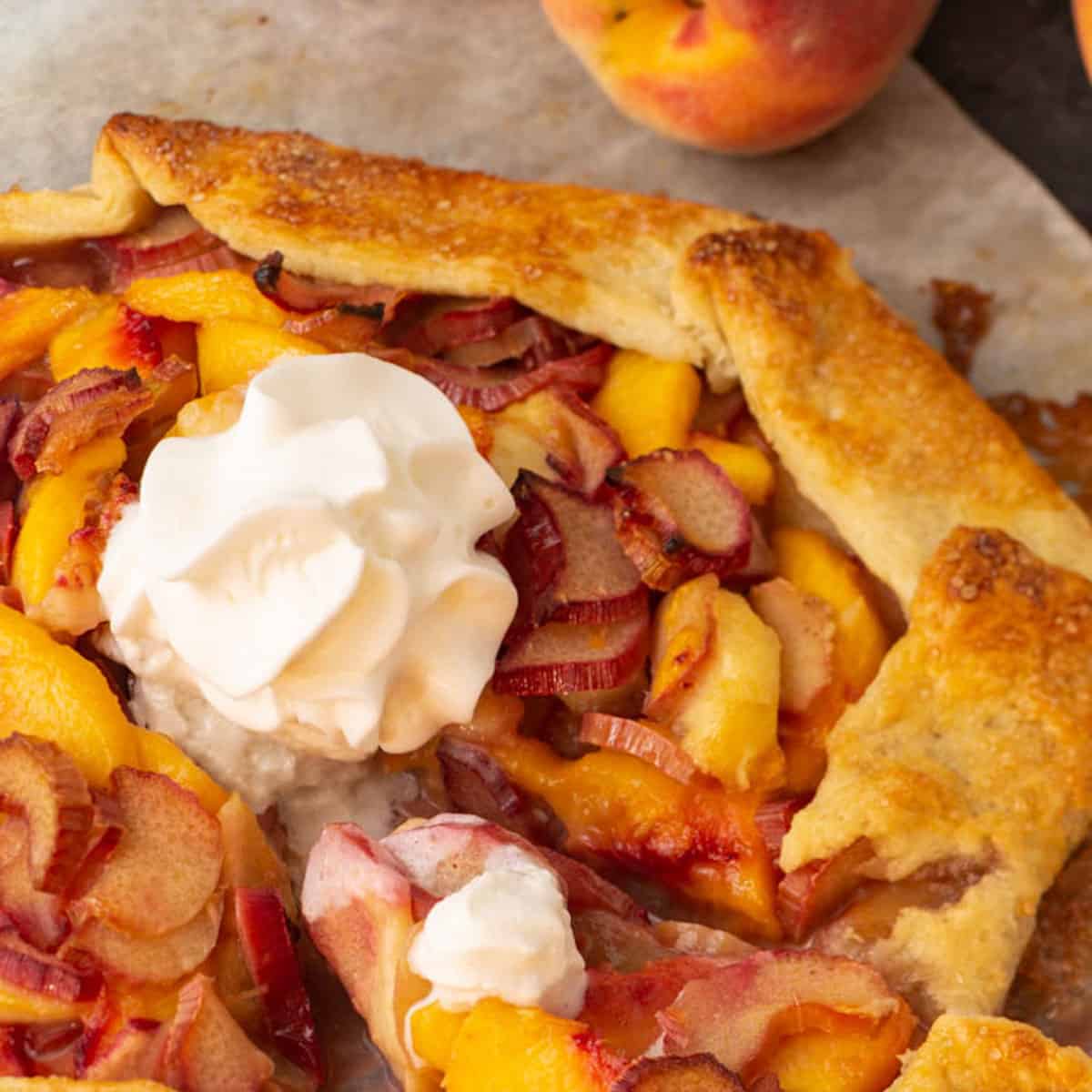 A peach and rhubarb galette with a slice being removed.