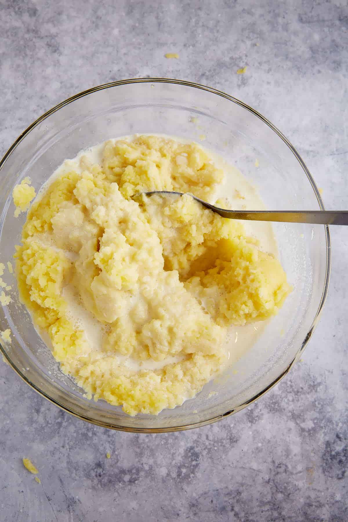 Cream added to mashed potatoes in a bowl.