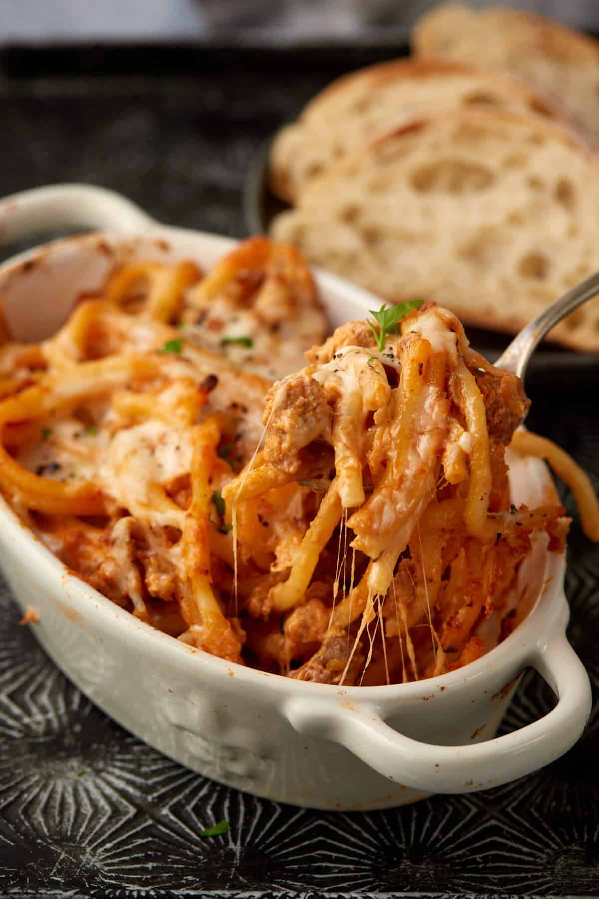 A spoon full of cheesy pasta being pulled from a dish.