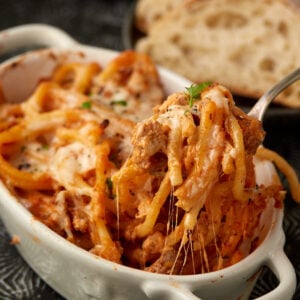 A serving of pasta being pulled out of a casserole dish.