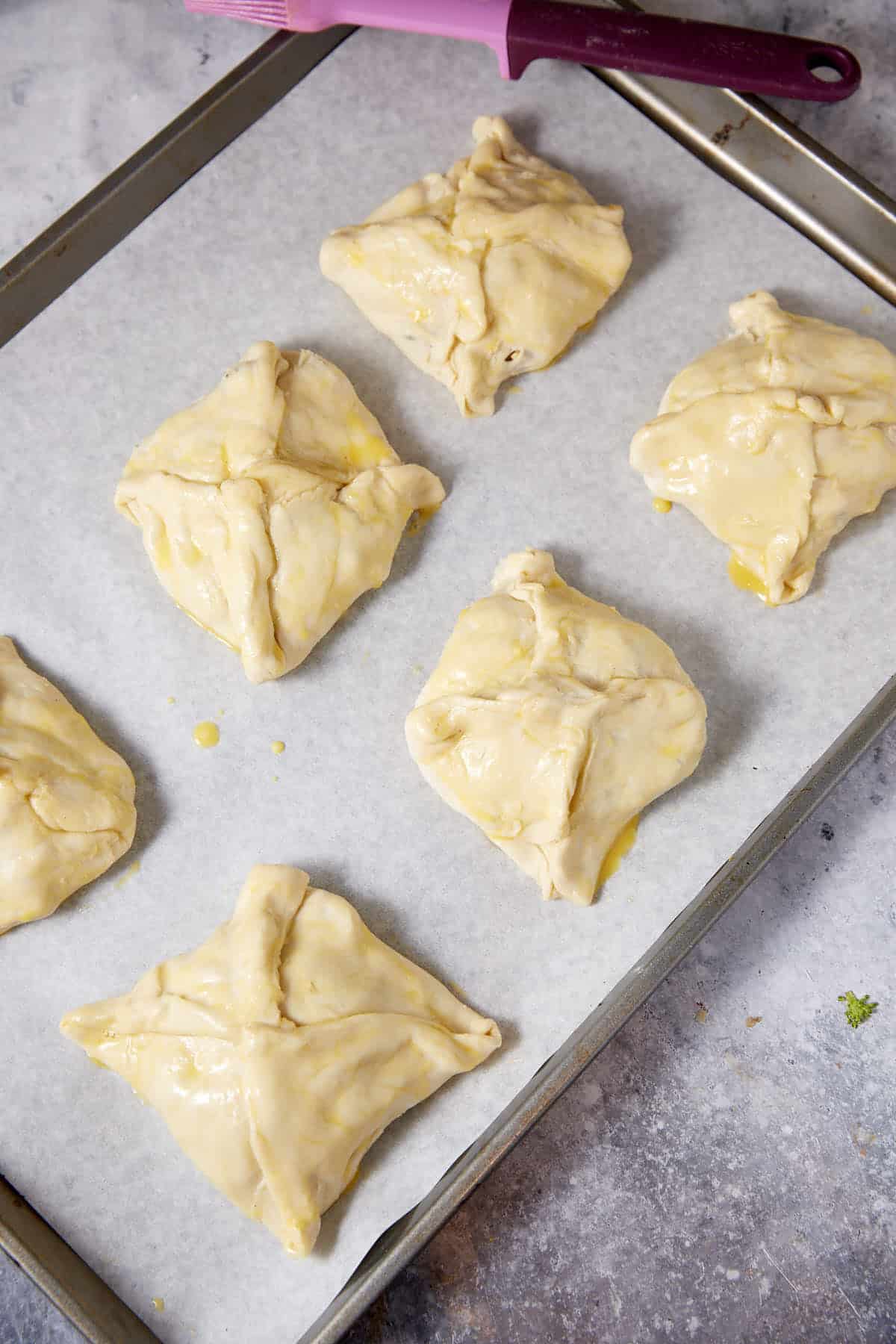 Puff pastry pockets on a baking sheet.