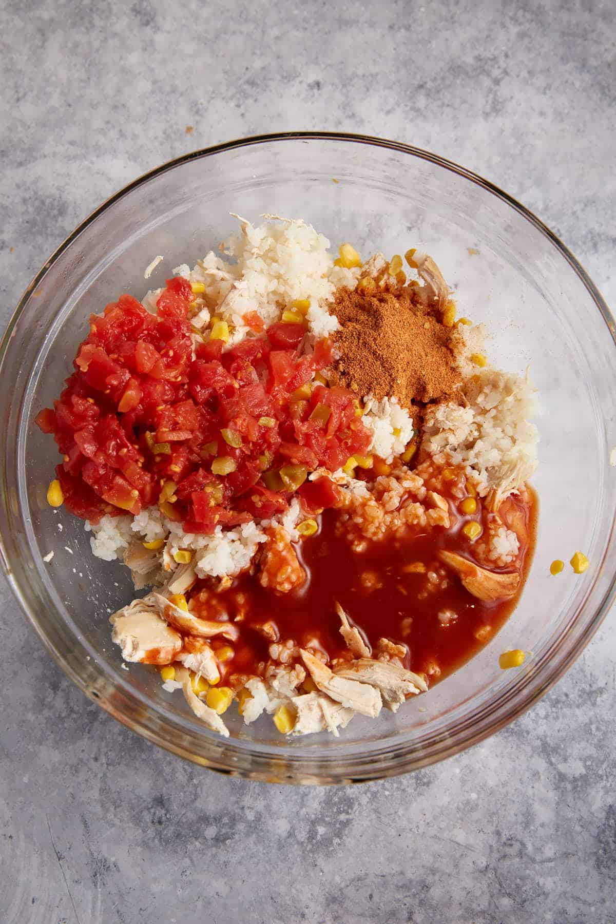 Tomatoes and seasoning added to chicken and rice.