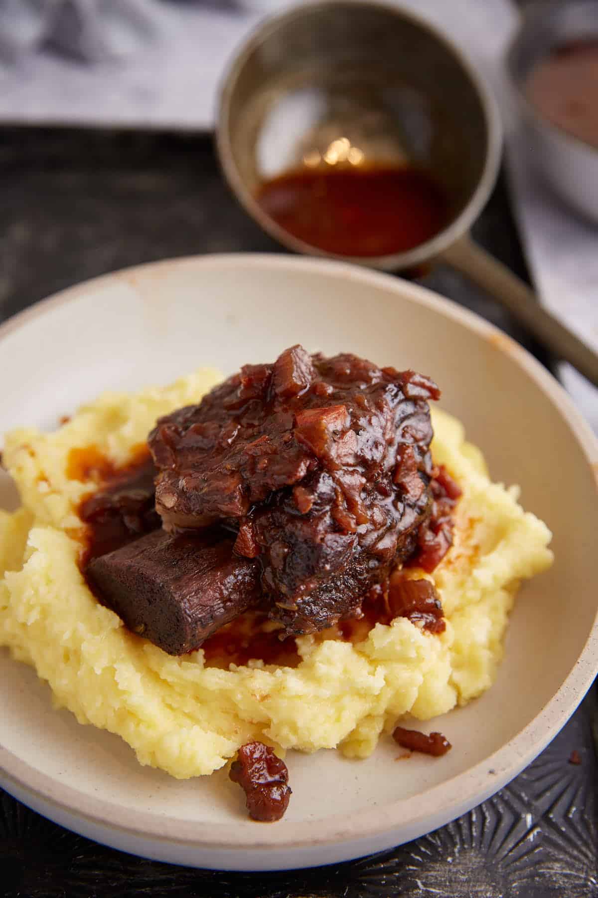A short rib on a plate covered with sauce.
