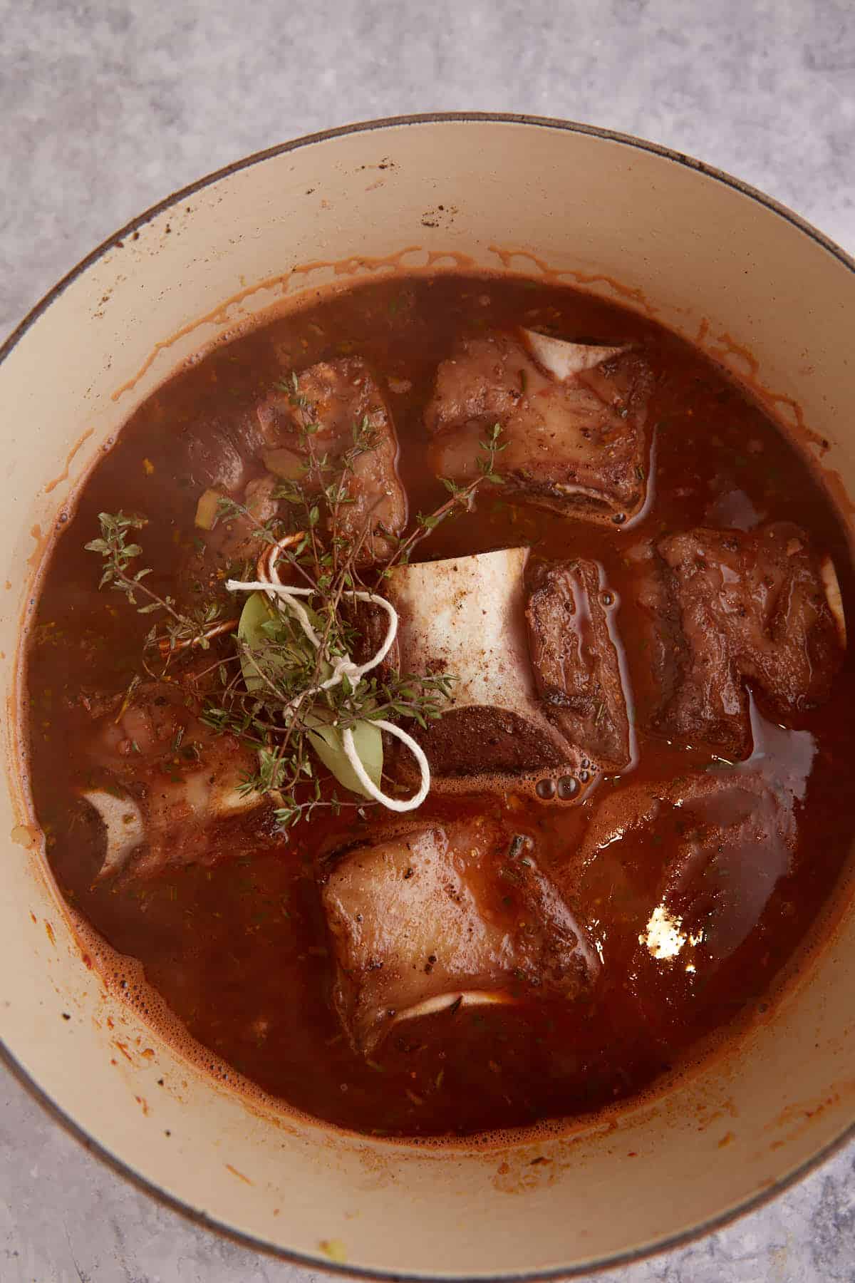 Ribs covered with broth in a Dutch oven.