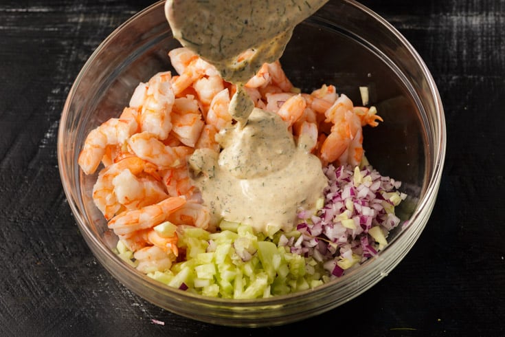 Dressing being poured over shrimp salad