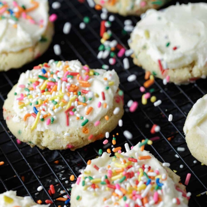 Frosted cookies with sprinkles being added.