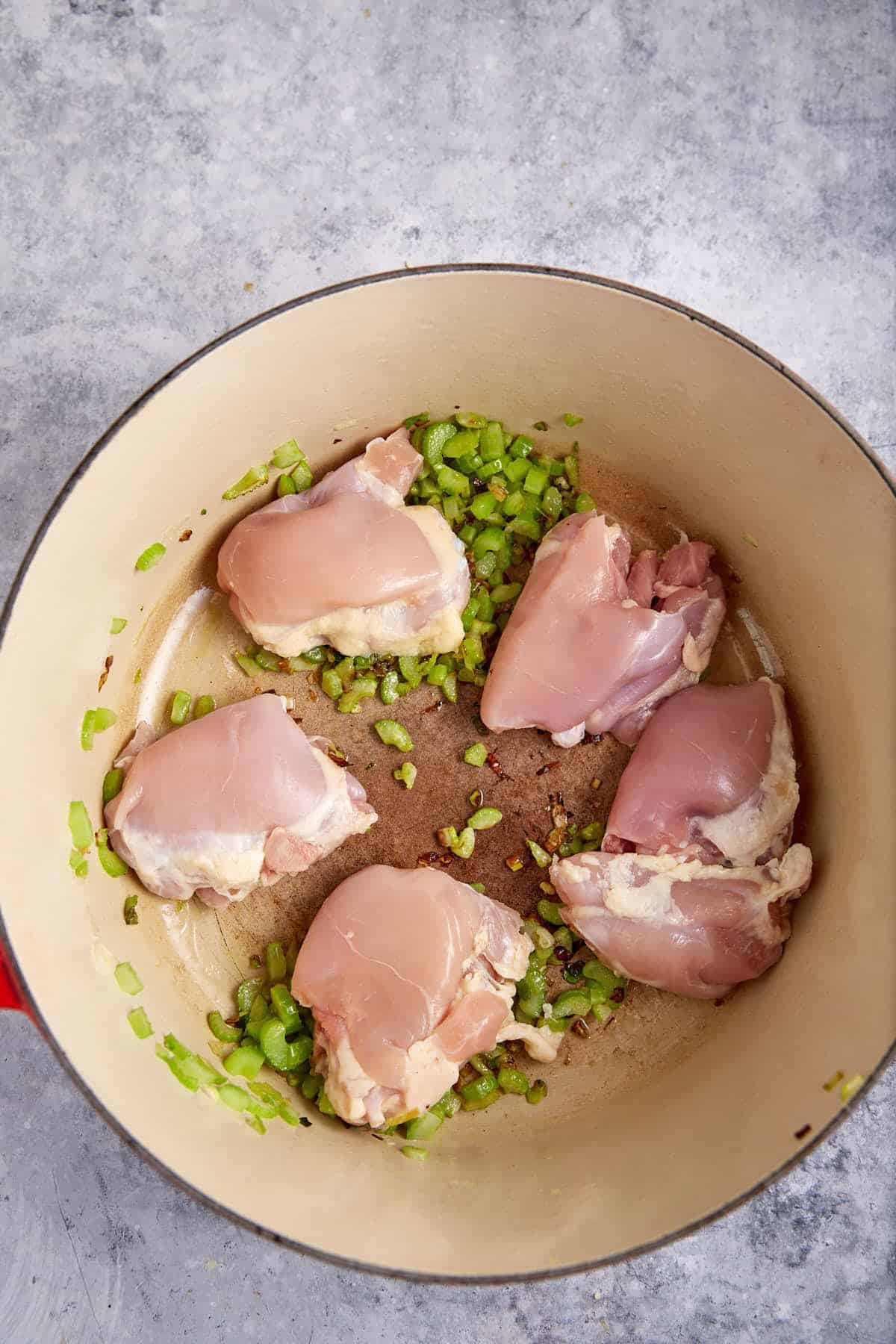 Chicken in a Dutch oven with celery and onions.