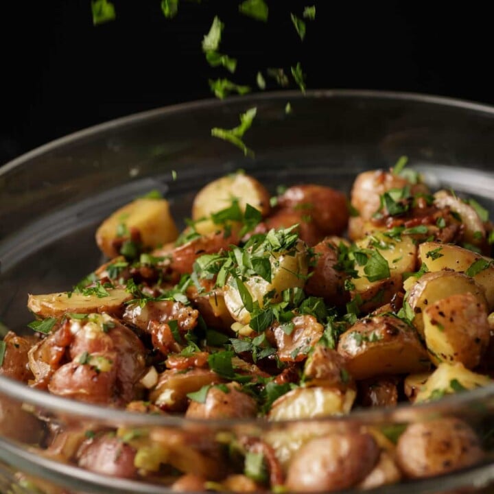 Parsley being sprinkled over warm potato salad