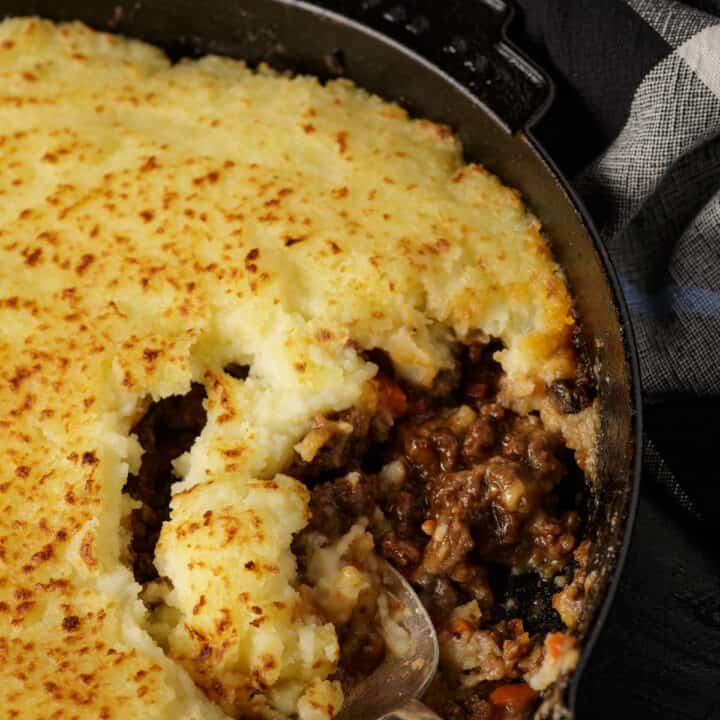 A skillet with shepherd's pie with a spoonful missing.