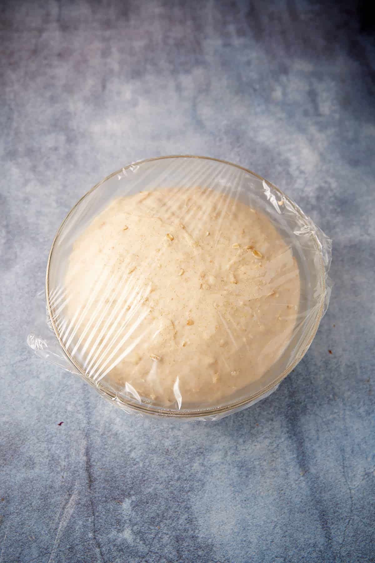 Honey oatmeal bread that has risen in a bowl.