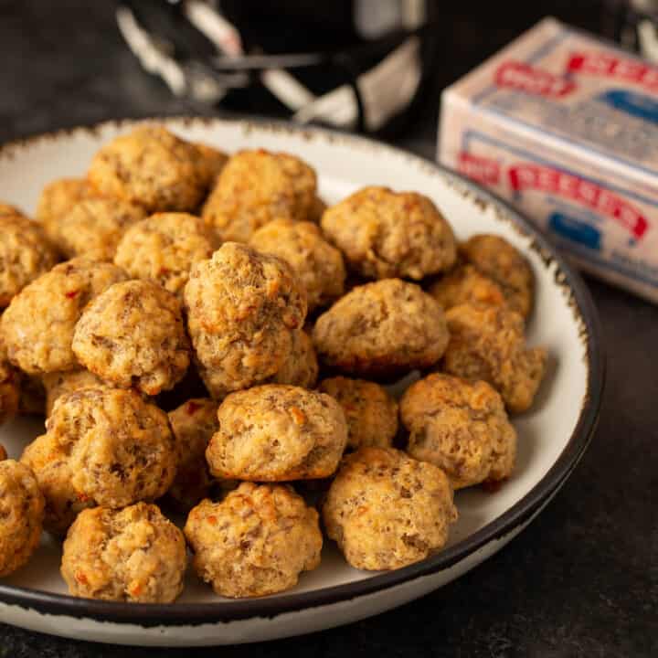 Pimento cheese sausage balls on a white platter with a football helmet in the background.