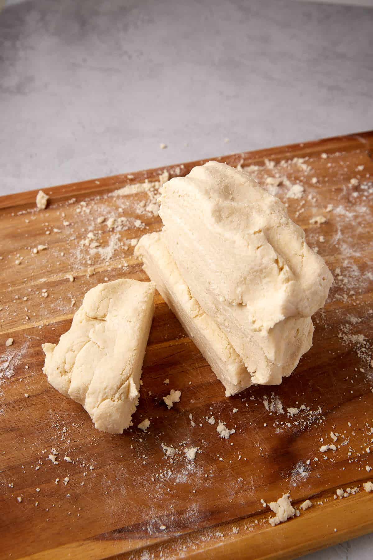 Sections of biscuit dough stacked on a cutting board.